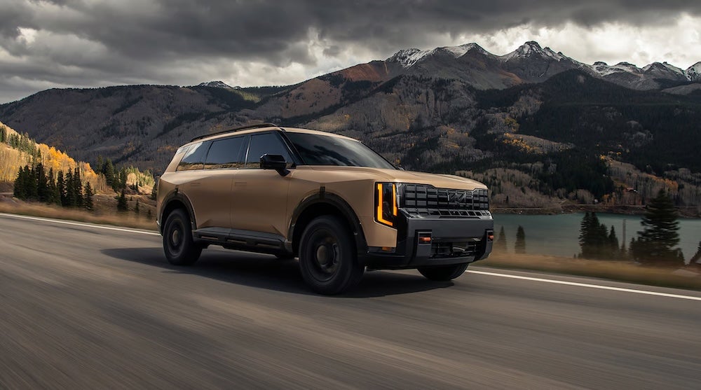 A brown 2027 Kia Telluride driving past mountains