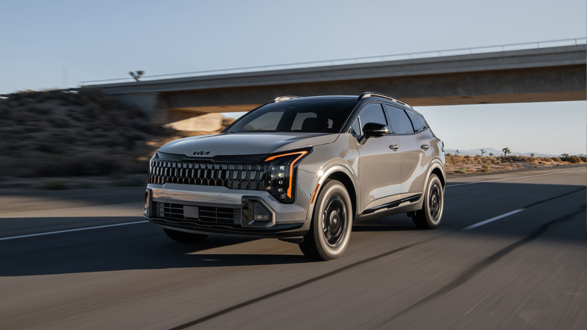 A light gray Kia Sportage driving past an overpass on a road in a desert