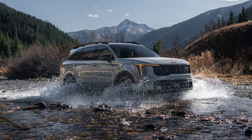 A gray 2026 Kia Sorento SUV driving through a shallow river